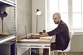 Focused serious adult business man working with documents and laptop in home office.