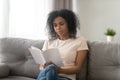 Focused serious African American woman reading book at home