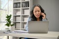 A focused and serious Asian senior businesswoman is on the phone with a business client Royalty Free Stock Photo