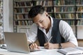 Focused serious Asian student guy with wireless earphones writing notes Royalty Free Stock Photo