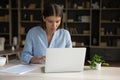 Focused serious employee girl using laptop, working from home