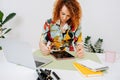 Attentive artist woman painting behind work desk on graphics tablet with stylus