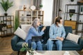 Focused serious senior couple sitting on sofa using laptop and talking. Royalty Free Stock Photo