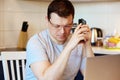 Focused and serious young man in glasses calls on a mobile phone at work sitting at his workplace. Online Job Concept. Self-isolat