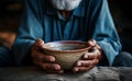 Focused shot empty bowl held by old mans hands, depicting hunger and poverty