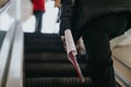 Focused shot of an individual's side with a watch, climbing up an escalator, gripping a rolled-up document or Royalty Free Stock Photo