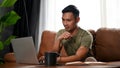 Focused and smart millennial Asian man looking at his laptop screen Royalty Free Stock Photo