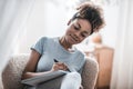 Focused smiling darkskinned woman writing at home