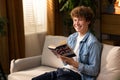 A focused, smiling student boy holds up an English dictionary and repeats new vocabulary words in his mind