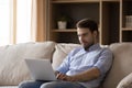 Focused smiling young business man working at laptop from home