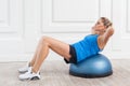 Focused sporty beautiful young athletic blonde woman in black shorts and blue top working in gym doing exercises for abdominal Royalty Free Stock Photo