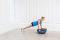 Focused sporty beautiful young athletic blonde woman in black shorts and blue top working in gym doing plank for abdominal muscles Royalty Free Stock Photo