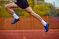 Focused sprinter on the verge of takeoff. Side view cropped photo of professional sportsman fast running on sport field Royalty Free Stock Photo