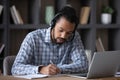 Focused student guy in headphones with mic writing notes Royalty Free Stock Photo