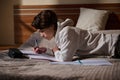 Student Lying on Bed Studying With Notebook and Pen in Cozy Bedroom Royalty Free Stock Photo