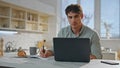 Focused student studying online sitting kitchen close up. Man working on laptop. Royalty Free Stock Photo