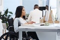 Focused on the task at hand. an attractive young businesswoman in a wheelchair working at her desk in the office. Royalty Free Stock Photo