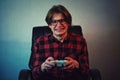 Focused teen boy playing video games late night seated in his chair. Angry and furious guy nerd wearing glasses, holding the Royalty Free Stock Photo