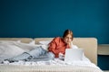 Focused teen girl working on study project on laptop lying in bed at home looking at screen.