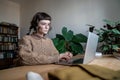 Focused teen student girl wearing glasses sitting at table typing on laptop