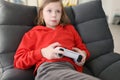 Focused teenage girl in red hoodie holds gaming console
