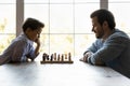 Focused thoughtful clever son and dad playing chess Royalty Free Stock Photo