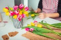 Focused Vase with flowers and blurred no face young man making spring bouquet using tulips. Online self-education of floristry. Royalty Free Stock Photo