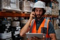 Focused warehouse manager tracking supply order details using digital tablet while in conversation over mobile phone in Royalty Free Stock Photo