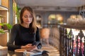 Focused woman in cafe using smartphone, open notebook and coffee cup on wooden table. Royalty Free Stock Photo