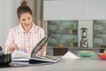 Focused woman checks a cookbook with interest