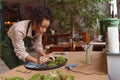 Focused woman decorator making green ikebana on tray with epoxy resin in florist workshop