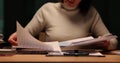 Focused woman diligently looks through documents at desk in evening in office