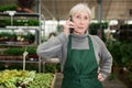 Focused woman garden shop owner having phone conversation Royalty Free Stock Photo