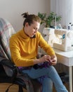 Busy female seamstress talking on mobile phone while sewing clothing at her workspace at home Royalty Free Stock Photo