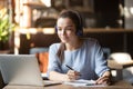 Focused woman wearing headphones using laptop, writing notes Royalty Free Stock Photo