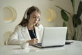 A focused woman wearing headphones, using a laptop, writing notes, a student studying a language, watching an online Royalty Free Stock Photo