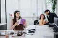 Focused businesswoman examining papers with colleagues discussing in background in bright modern office Royalty Free Stock Photo