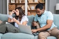 Focused worried couple paying bills online on laptop with documents sitting together on sofa at home, serious confused man and Royalty Free Stock Photo