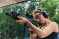 Focused young adult European woman looking through the rifle loupe and preparing for a competition at shooting range Royalty Free Stock Photo