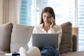 Focused young adult laptop user girl talking on mobile phone Royalty Free Stock Photo