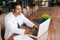 Focused young African male doctor in white coat working typing on laptop computer sitting at desk. Royalty Free Stock Photo