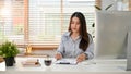 Focused young Asian businesswoman examining business financial data report at her desk Royalty Free Stock Photo