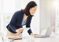 Focused young asian businesswoman using a digital tablet device and laptop while planning notes at a desk in an office Royalty Free Stock Photo