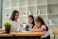 A focused young Asian elementary school girl is studying with a private tutor with her friend Royalty Free Stock Photo