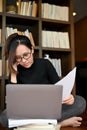 Focused young asian female freelancer or writer concentrated reading some content on laptop