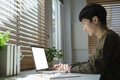 Focused young asian man working online, reading business email on laptop computer