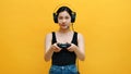 Focused young asian woman with headset and joystic controller playing video games. Isolated on yellow background Royalty Free Stock Photo