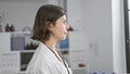 Focused young and beautiful hispanic female scientist with a serious face, looking off to the side in her busily working lab, Royalty Free Stock Photo