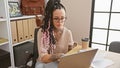 Focused young and beautiful hispanic woman working hard on her laptop at the office, embodying success and professionalism Royalty Free Stock Photo