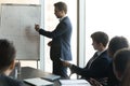 Focused young business trainer explaining hand drawn charts on whiteboard. Royalty Free Stock Photo